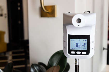 Infrared thermometer at entrance of commercial shop to scan visitor temperature as new normal requirementの写真素材