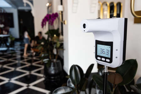 Infrared thermometer at entrance of commercial shop to scan visitor temperature as new normal requirementの写真素材