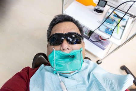 Asian man with rubber sheet named dam installed during dental orthodontic surgery to isolate saliva interferance.の写真素材