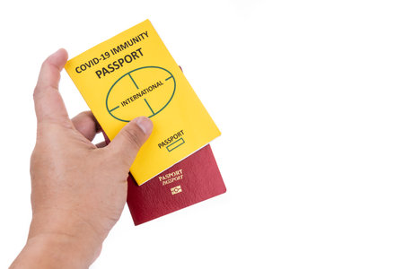 Hand holding conceptual Covid-19 Immunity Passport for travel permission and regular passportの写真素材
