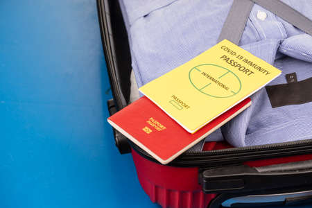 Concept of covid-19 Immunity Passport for international travel with clothes packed in luggage bag ready for travelの写真素材