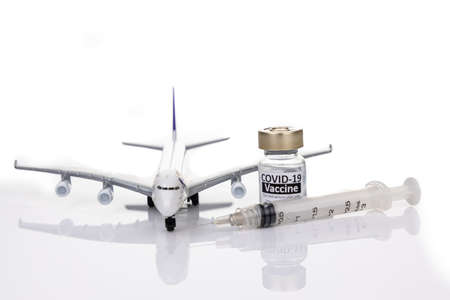 Conceptual travel restriction with coronavirus vaccine vial, syringe and model passenger airplaneの写真素材