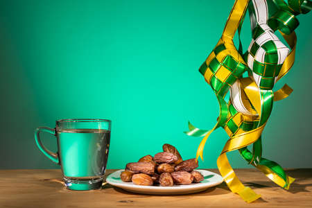Muslim iftar of breaking of fast during Ramadan month with preserved sweet dates and water. Ketupat as prop.の写真素材