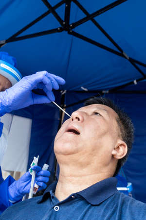 Mature asian man doing covid 19 PCR nasal swab test via nostril