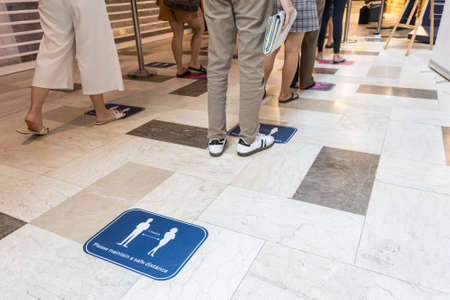 People queue in line for physical social distance to enter supermarket for safetyの写真素材