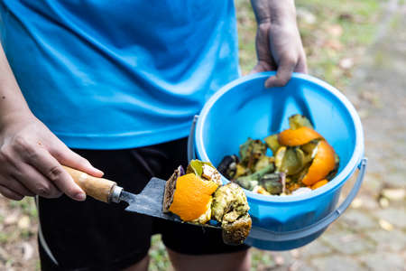 Person with bucket consisting organic kitcjhen waste grreens for recycle into compostの写真素材