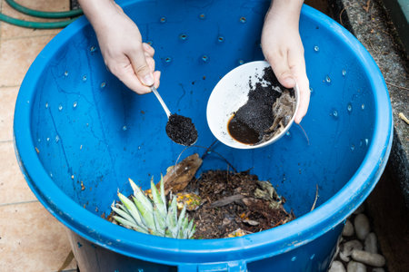 Hand adding coffee grounds into the compost bin as part of green compost materialの写真素材