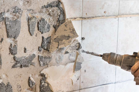 Worker use demolition hammer drill to break up tiles from wall surface. Motion blur intended.の写真素材