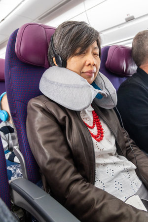 Asian woman with soft and comfortable neck pillow relaxing during longhaul airplane flightの写真素材
