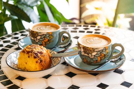 A cuppo of coffee latte with art and cakes in a cafe with relaxing and peaceful ambient surroundingの写真素材