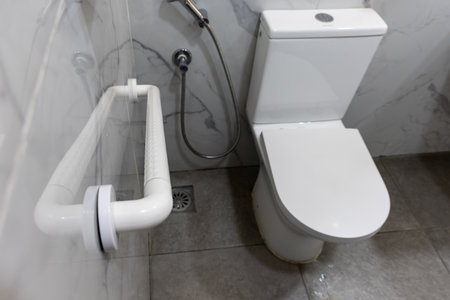 Safety Hhand rail fixture on wall inside wc next to toilet bowl to aid users with physical health...