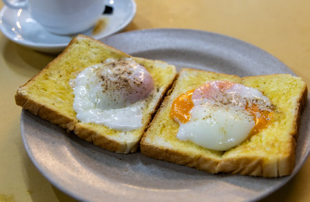 Close up on roti bakar telur goyang or toast bread with half boiled eggs, popular breakfast delicacy...