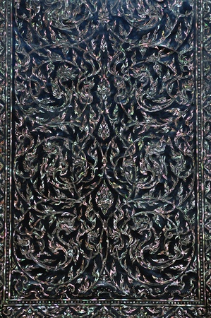Traditional Thai art on black wood carving door decorated with Mother of pearl inlay.の写真素材