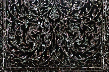 Traditional Thai art on black wood carving door decorated with Mother of pearl inlay.の写真素材