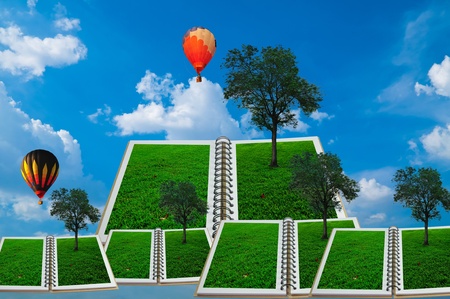Open book with tree and hot air balloon over green field and blue skyの写真素材