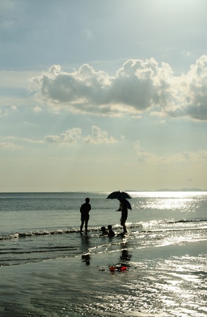 Silhouetted family playing at the beachの写真素材