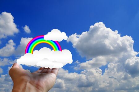 hand of businessman hold rainbow and cloud to the blue skyの写真素材