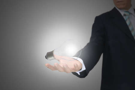 Light bulb in hand business man on grey backgroundの写真素材