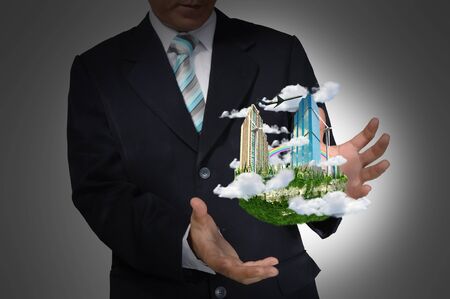 Business Man holding floating city on grey backgroundの写真素材
