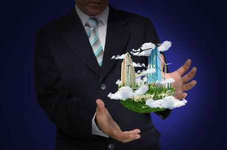 Business Man holding floating city on blue backgroundの写真素材