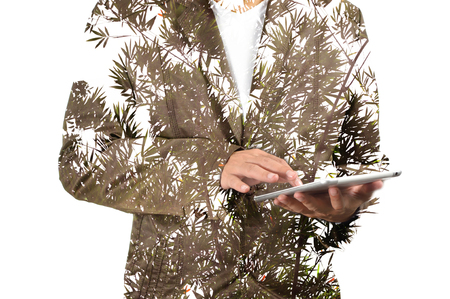 Double exposure portrait of Business man using digital tablet with Bamboo tree and leavesの写真素材