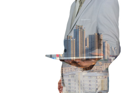 Double exposure of a businessman and a city using a tablet over white backgroundの写真素材