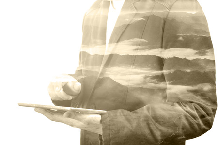 Businessman with Digital Wireless Tablet and Mountain Nature Background with Fog, Double Exposure as Environment Concept.の写真素材