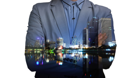 Young man in suit and with folded arms on abstract illuminated night city background. Double exposureの写真素材