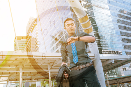 Double Exposure of Confident young man, holding suit with Briefcase, looking at his watch while standing outdoors with Clock , In time appointment Concept.の写真素材