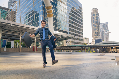 Happy Young handsome businessman walking outdoors in Modern City morningの写真素材