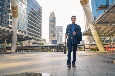 Happy Young handsome businessman walking outdoors in Modern City morningの写真素材