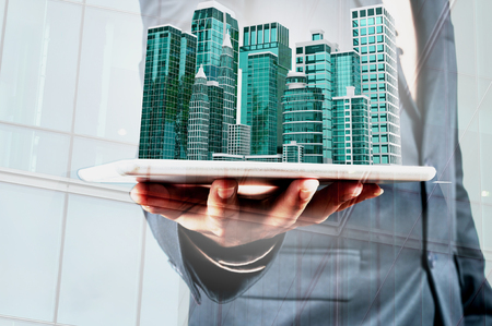 Double Exposure of Businessman use Digital Wireless Smart Touch Screen Tablet with Modern Building as Real Estate Project Development or Construction Concept.の写真素材