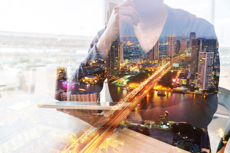 Double Exposure of Man or Male hold Digital Wireless Smart Tablet with City Building Business Street and Bridge as High Speed Data Technology Innovation Networking and Real Estate ProJect Development Concept.の写真素材