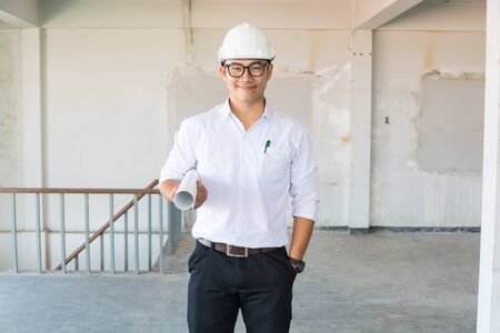 Businessman or Architect Engineer wear Hardhat in White Shirt holding Blueprint in construction Site as Business Real Estate Project Development concept.の写真素材