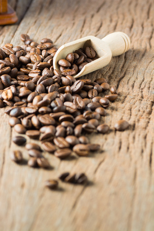 Stack of Fresh Raw Coffee Beans on Wooden Desk Table with Wooden Spoon and Coffee Grinder as Refresh Beverages Conceptの写真素材