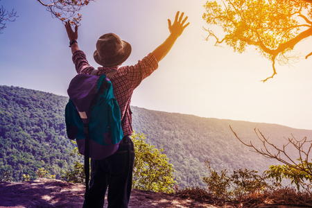 Cheering Young Male Traveler Backpacker spread out hand express felling Freedom successful while travel Trekking over the cliff Mountain as Modern Hiker Lifestyle recreationの写真素材