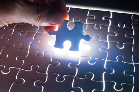 Male or Man Hand and Finger put Piece of Jigsaw in Place to Solve or Match Puzzle as Business Solutionの写真素材