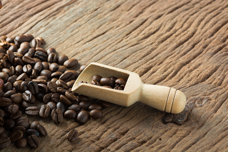 Pile of Fresh Raw Coffee Beans on Wooden Desk Table with Wooden Spoon as Refresh Beverages Concept.の写真素材
