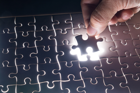 Male or Man Hand and Finger put Piece of Jigsaw in Place to Solve or Match Puzzle as Business Solutionの写真素材