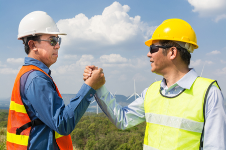 Architect and Engineer shake hand beside wind Turbine Power Generator Field as Project Development Company Agreement Joint Venture concept.の写真素材