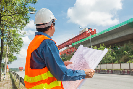 Engineer or Architect wear white Helmet working or reading Construction Plan in Highway or Autobahn Construction site as Industrial or infrastructure Contractor Concept.の写真素材