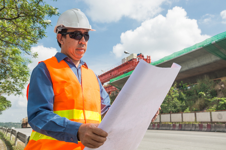 Engineer or Architect wear white Helmet working or reading Construction Plan in Highway or Autobahn Construction site as Industrial or infrastructure Contractor Concept.の写真素材