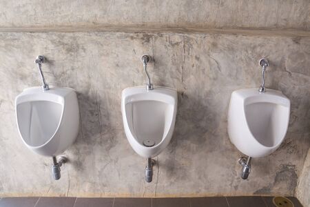 Close up of White Male urinal with Bare cement wall