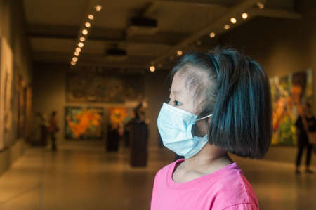 Girl Wearing Medical Mask while traveling in Public Art Museum or Gallery Hall as New Normal Lifestyle Traveling in Situation of Covid-19 or 2019 Pandemic Disease.の写真素材