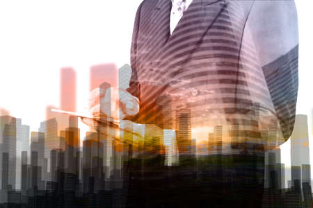 Double Exposure of Businessman hold Digital Wireless Table with City Building and Skyscraper as Concept of Real Estate or Technology business administration.の写真素材