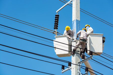 Group of Male Engineer or Electrician working on Crane Bucket over Electrical Pole with 
Hardhat and Safety tools as Maintenance Services for Power industry line or Technology Communication Cable.の写真素材