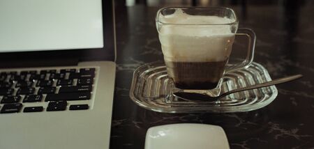 White cup of black coffee and notebook on the table when workingの写真素材