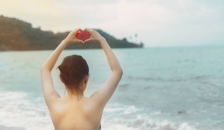 A white woman with hearth hand symbol with sea backgroundの写真素材