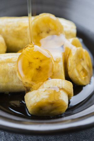 Banana slices with honey syrup in a black vintage dishware.の写真素材