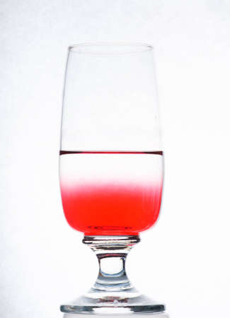 Red syrup in water. In a wine glassの写真素材